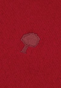 Tessuto a maglia rosso con un piccolo design di un albero ricamato di colore marrone. La consistenza è morbida con costine visibili in tutto il materiale.