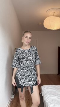 Melnā un baltā zebras raksta blūze ar īsām piedurknēm un mezgla detaļu viduklī, apvienota ar spītīgi melnu mākslīgās ādas svārku.