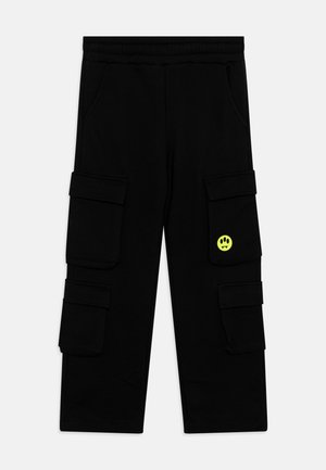 Pantaloni cargo neri realizzati in tessuto morbido, con tasche laterali, una vita elasticizzata e una toppa con logo a forma di faccina sorridente gialla sul davanti.