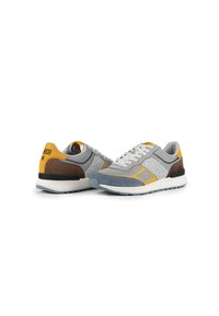 Scarpe sportive grigie in materiali mesh e suede, con accenti gialli, un design testurizzato e lacci bianchi. Suola in gomma per una buona aderenza.
