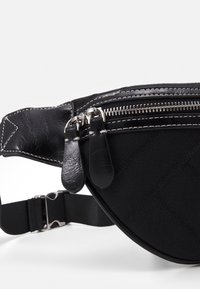 Borsa in tessuto nero e pelle con doppi zip argentati e tracolla regolabile con fibbia argentata.