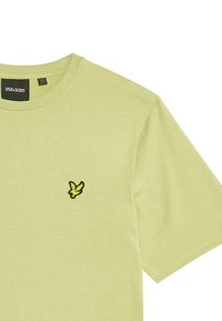 Lys grøn bomulds t-shirt med rund hals og korte ærmer. Har et lille broderet logo i sort og gult på brystet.
