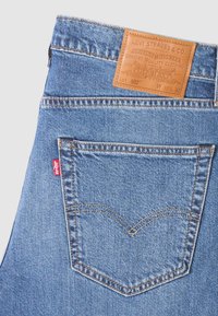 Blue denim jeans with a classic design. Features a leather label at the waist, a red Levi's tab, and distinct back pocket stitching.
