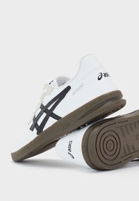 Pantofi sport albi cu accente negre și gri. Caracteristici: profil jos, superior din piele netedă, închidere cu șireturi și talpă exterioară din cauciuc texturat.