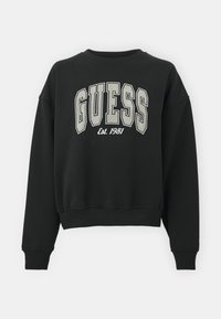 Felpa nera con polsini e orlo a coste. Presenta un grande logo "GUESS" in bianco e grigio. Progettata con collo rotondo e vestibilità ampia.