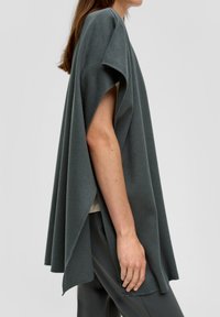 Kolenstofgrijs, gebreide poncho met losse mouwen en een vloeiend ontwerp. Heeft een zachte textuur en valt elegant om het lichaam.