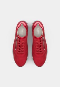 Sneaker rossi con una finitura liscia e lucida, texture perforata sulla parte superiore, chiusura con lacci e cerniera laterale per un facile accesso.