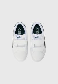 Baskets blanches avec une tige en cuir lisse, des bandes Velcro, des accents verts sur le talon et une semelle intérieure rembourrée.