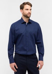 Camicia a maniche lunghe blu navy con chiusura a bottoni, taschino sul petto e un tessuto liscio e strutturato.
