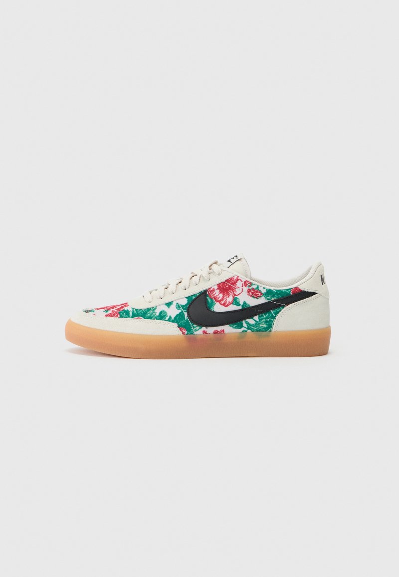 Nike sneakers with a floral pattern in red and green on a cream background, featuring a black swoosh and gum rubber outsole.
