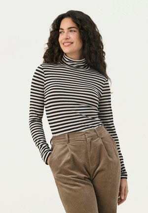 Striped long-sleeve turtleneck top in black and cream, paired with high-waisted brown corduroy pants. Soft fabric, fitted design.