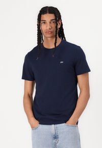 Marineblå bomull t-skjorte med rund hals og korte ermer, med en liten brodert logo på brystet. Avslappet passform, glatt tekstur.