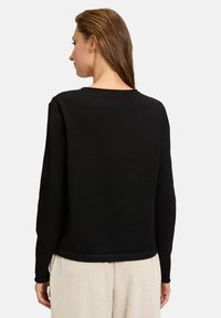 Schwarzer Pullover mit rundem Halsausschnitt und langen Ärmeln, von hinten präsentiert. Glatte Textur, taillierte Silhouette und dezente Saumdetails.