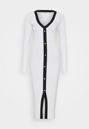 Biała, prążkowana sukienka midi z długim rękawem, czarnym wykończeniem przy dekolcie w kształcie litery V, guzikach z przodu oraz rozcięciem u dołu.
