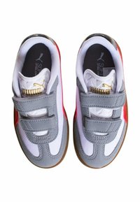 Sneaker grigie e bianche con accenti rossi, chiusura in velcro, suola in gomma e sovrapposizione in tessuto testurizzato. Finiture dorate con logo del brand.