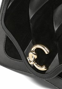 Borsa a mano in pelle nera con pannelli in camoscio trapuntato e logo in metallo dorato. Texture liscia con superfici opache e lucide a contrasto.