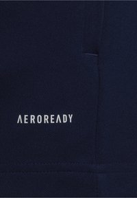 Tissu de sport bleu marine avec une surface texturée et des coutures visibles. Logo "AEROREADY" imprimé en blanc dans le coin inférieur gauche.