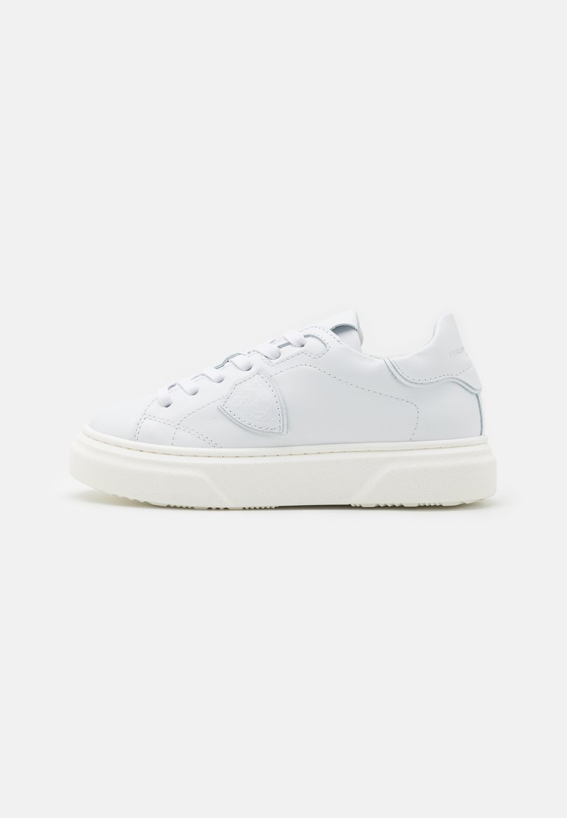 Baskets en cuir blanc avec une texture lisse, bout rond, lacets plats et une semelle en caoutchouc épaisse. Présentent une marque minimaliste et des coutures discrètes.