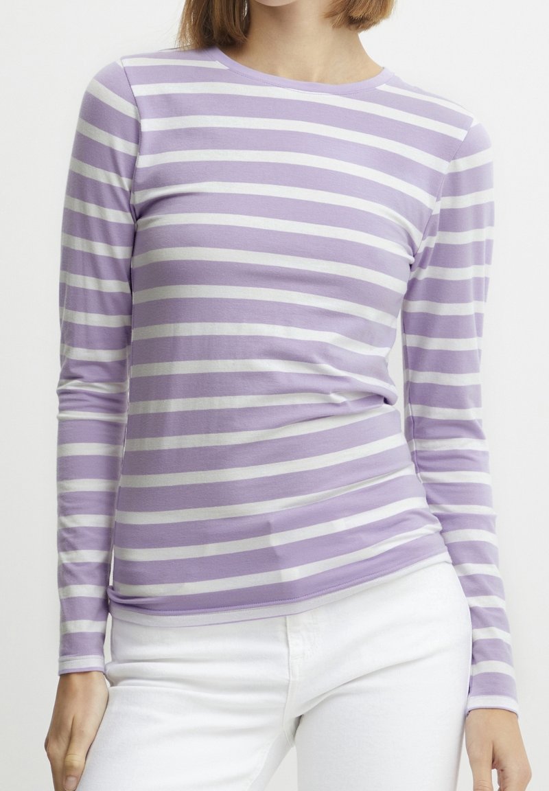 Långärmad skjorta i ljuslila med vita horisontella ränder. Tillverkad av mjukt material med rundad halsringning och figursydd design.