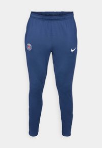 Mornarsko modre športne hlače z elastičnim pasom, zožani nogi, belo Nike logo in zgornjem levem stegnu je logo Paris Saint-Germain.
