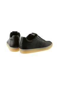 Para czarnych skórzanych sneakersów niskich z podeszwami w kolorze gumowym, widocznym szwem i subtelnym wytłoczonym wzorem z boku.