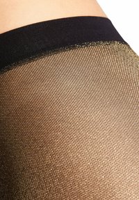 Czarna talia u góry przechodzi w przezroczystą, złotą i czarną siateczkę. Drobny wzór siateczki na całej powierzchni, dodający tekstury i detali.