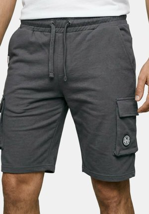 Shorts cargo gris charbon avec taille à cordon, portés par une personne, comportant des poches latérales et un écusson circulaire sur la poche droite.
