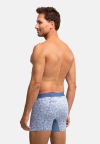 Boxer da uomo blu a fantasia con una vita in tessuto testurizzato, caratterizzati da un design geometrico in azzurro su blu, con una vestibilità aderente e lunghezza a metà coscia.