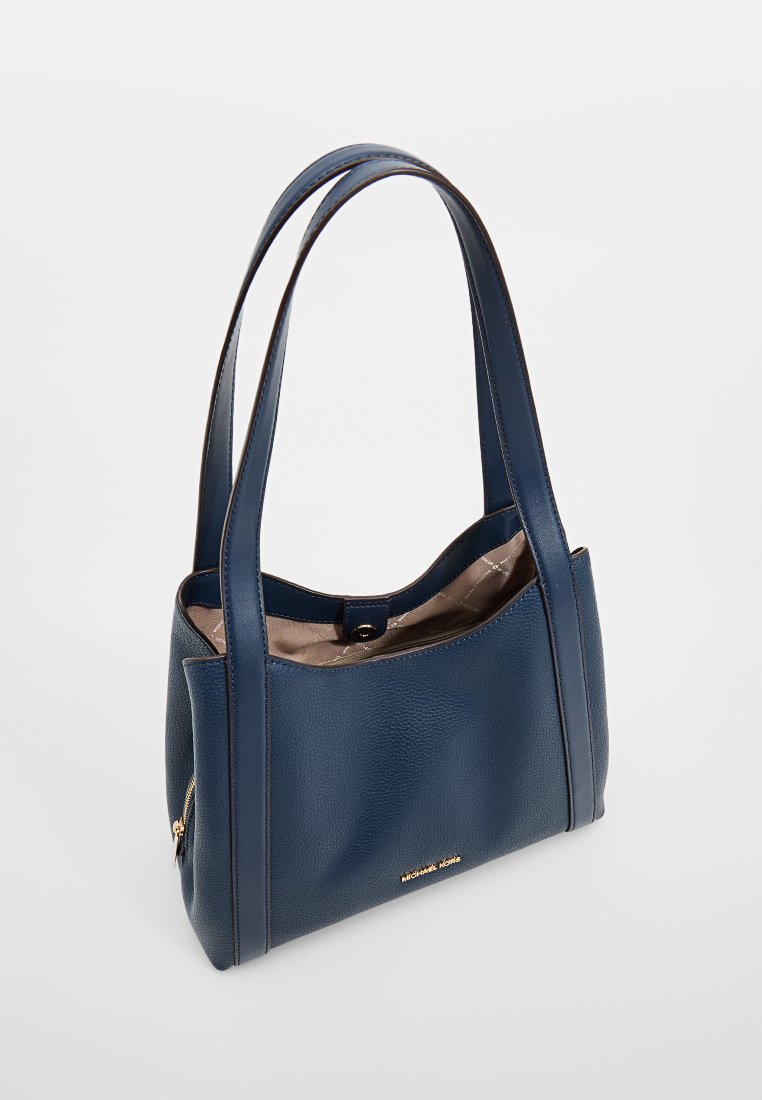 Sac fourre-tout en cuir bleu marine avec deux poignées, ouverture supérieure avec bouton pression, doublure intérieure beige et logo doré de Michael Kors.
