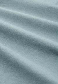 Helles blaues Baumwollgewebe mit glatter Textur, das sich sanft drapieren lässt und feine Rippmuster auf der Oberfläche aufweist.