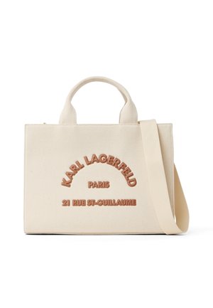 Sac fourre-tout en toile crème avec des poignées courtes et une bandoulière longue, embossé avec l'inscription "Karl Lagerfeld Paris 21 Rue St-Guillaume" en lettres marron.