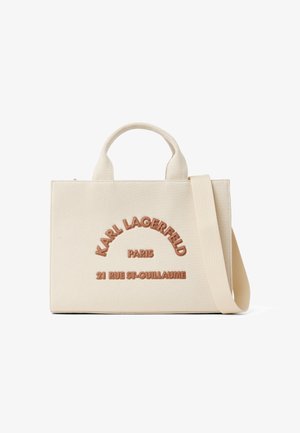 Kremowa torba na ramię ze sztywnym materiałem, krótkimi uchwytami i długim paskiem, z brązowym tłoczonym napisem "Karl Lagerfeld Paris 21 Rue St-Guillaume".