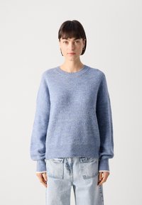 Light blue knitted sweater with a round neckline, balloon sleeves, and ribbed texture, paired with high-waisted denim jeans.