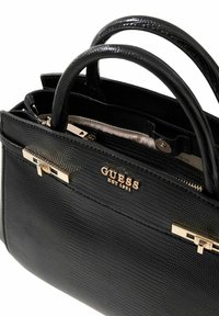 Sac à main structuré noir avec une finition texturée, doté de deux anses et de ferrures dorées, comprenant une plaque avec logo et un détail de fermoir.