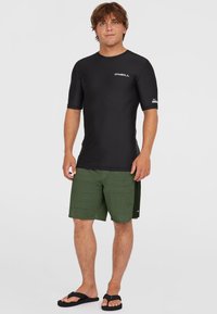 T-shirt med kortärmar i svart med O'Neill-logotyp, matchad med olivgröna badshorts med ett texturerat mönster och svarta flip-flops.