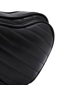 Borsa nera in pelle con dettagli a trapunta e cuciture a contrasto. Presenta una superficie liscia e una forma arrotondata, con chiusura con zip.
