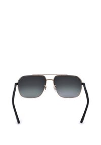 Lunettes de soleil rectangulaires avec une fine monture métallique dorée, des verres dégradés gris foncé et des branches noires avec des plaquettes de nez sur fond blanc.