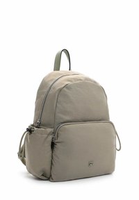 Beige nylonreppu, pyöreä muoto, etutasku, kaksoisvetoketjut ja säädettävät olkahihnat; alareunassa hienovarainen logo.