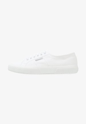 Weiße Low-Top-Canvas-Sneaker mit Gummisohle, Schnürverschluss und dezentem Markenetikett auf der Seitenfläche.