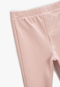 Vaaleanpunaiset legginsit, jotka on valmistettu pehmeästä ja joustavasta kankaasta. Varustettu elastisella vyötärönauhalla ja sivusaumoilla, joilla on sileä rakenne.