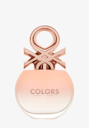 Flacon de parfum rond dégradé rose avec bouchon géométrique en or rose, étiqueté "COLORS WOMAN DE BENETTON."