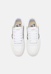 Hvit sneakers med overdel i lær og semsket skinn, med grå detaljer og gummisåler. Snøringene er hvite og runde. Klassisk Vans-merke inkludert.