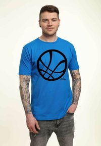 Camiseta de algodón azul con un gran gráfico de baloncesto negro en el frontal. El diseño incluye un escote redondo y un corte relajado.
