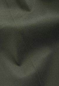 Tissu lisse vert olive foncé avec une légère texture diagonale et des plis doux créant des ombres.