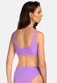 Fioletowy bikini o fakturowanym wykończeniu, z szeroką opaską na biust i odkrytymi plecami, w komplecie z pasującymi majtkami o niskim stanie, które prezentują gładkie wykończenie.