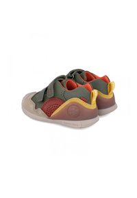 Scarpe multicolori caratterizzate da una combinazione di materiali verdi, marroni e gialli. Hanno una finitura testurizzata, cinturini in velcro e una suola curva.