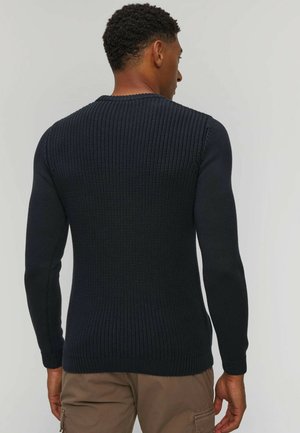 Maglione lavorato a maglia blu navy con maniche lunghe, caratterizzato da un motivo testurizzato e un collo rotondo a coste. Indossato al rovescio, mostrando il dettaglio sul retro.