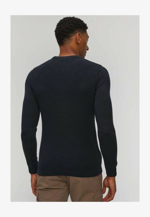 Maglione lavorato a maglia blu navy con maniche lunghe, caratterizzato da un motivo testurizzato e un collo rotondo a coste. Indossato al rovescio, mostrando il dettaglio sul retro.