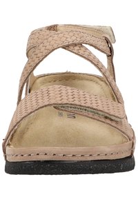 Beige woven strap sandals with a cushioned insole, open toe design, and black textured rubber sole. Features crisscross straps and stitching.