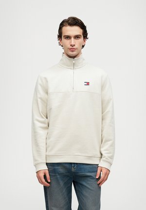 Felpa mezza zip beige chiaro realizzata in morbido materiale felpato, con una striscia sul petto, piccolo logo e polsini e orlo a coste.